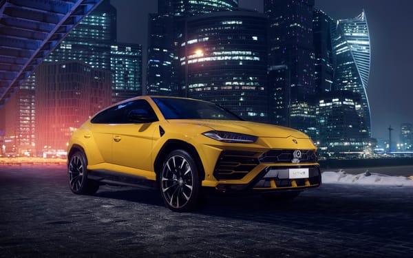Обои Желтый Lamborghini Urus на фоне ночных небоскребов