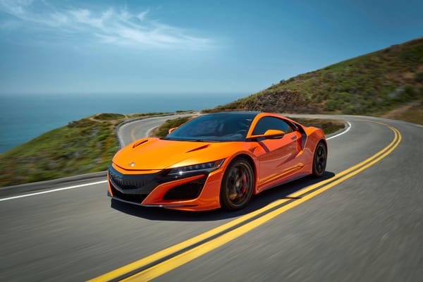 Обои Оранжевый автомобиль Honda NSX на трассе под голубым небом