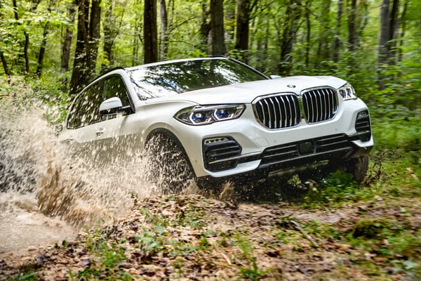 Обои Белый внедорожник BMW X5 едет по грязи в лесу